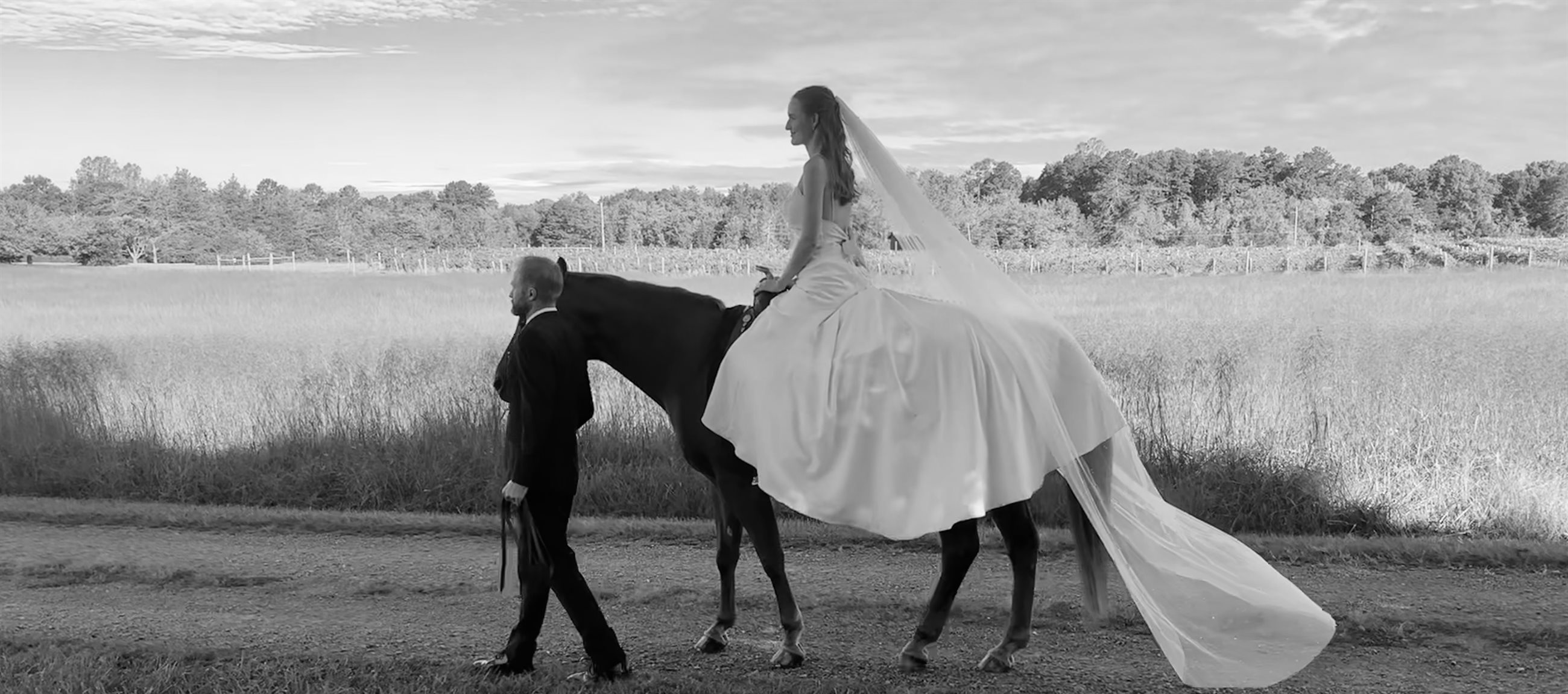 Bride riding through the meadow on horseback, led by the groom