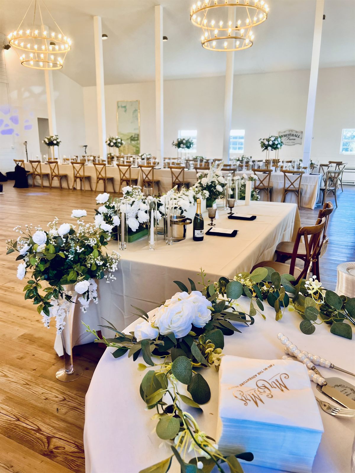 Reception table with white florals beneath the winery chandeliers